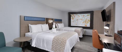 Habitación de hotel con dos camas, un escritorio, una silla, un televisor y una obra de arte colgada en la pared.