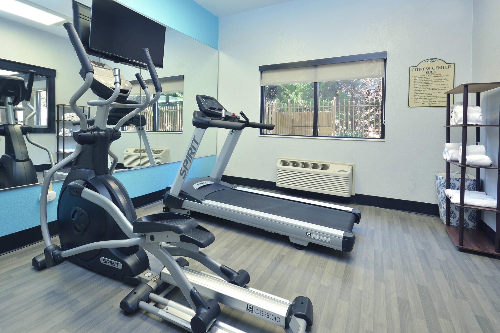 Un gimnasio con cintas de correr, una elíptica y un espejo grande.