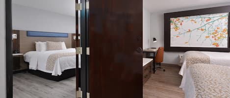 Habitación de hotel con cama, escritorio, silla y un ventanal con un cuadro.
