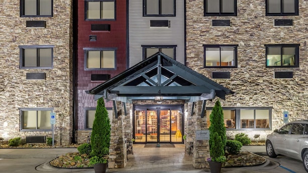 A hotel entrance with a stone facade, a covered entryway, and a parking area.