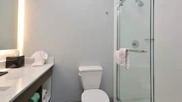 A bathroom with a toilet, a glass shower enclosure, and a vanity with a mirror.