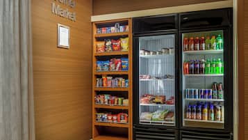 A corner market with shelves stocked with snacks and a refrigerated display with beverages.