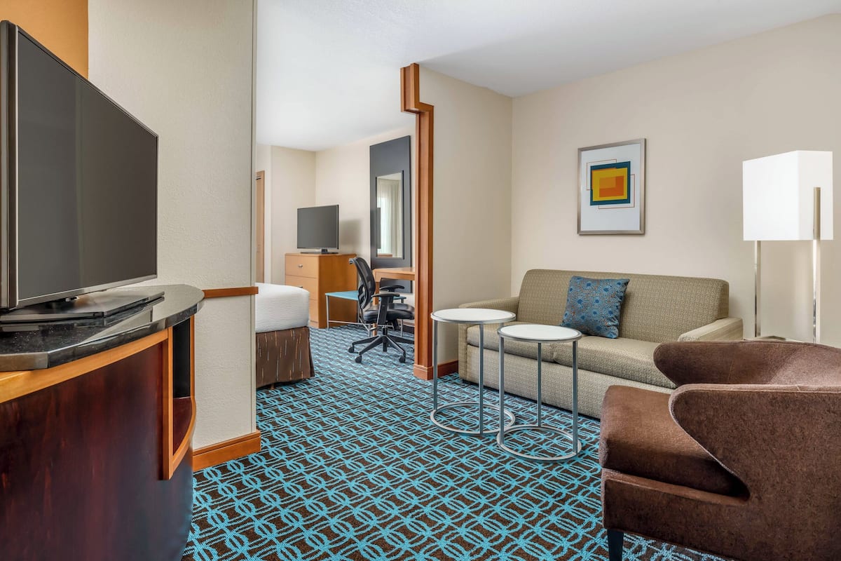 Habitación de hotel con televisión de pantalla plana, sofá, pequeña mesa, escritorio y silla.