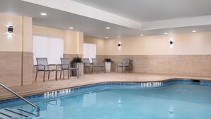A swimming pool with a tiled edge, surrounded by chairs and tables, and recessed lighting on the ceiling. - Fairfield Inn & Suites by Marriott Dallas Mansfield (Mansfield)