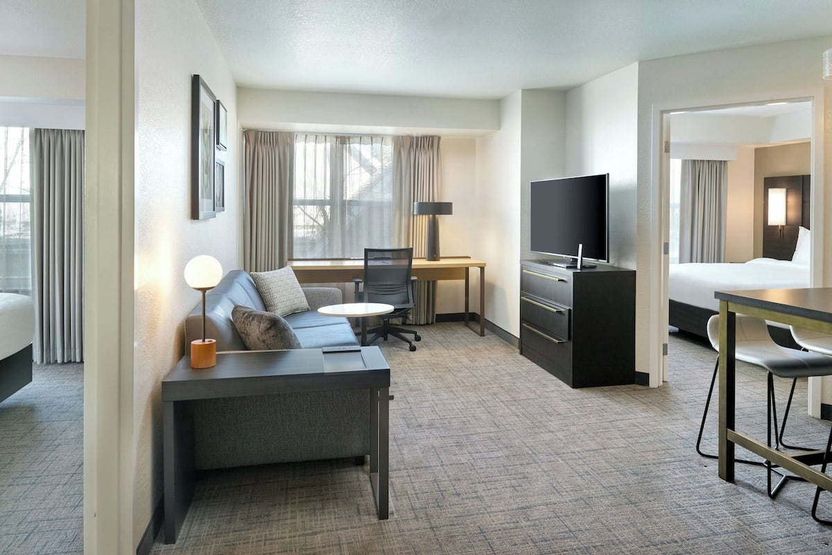 A hotel room with a sofa, a desk, a TV, and a bed.