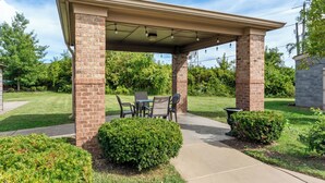 A covered patio area with a brick column structure, outdoor furniture, and well-maintained landscaping.