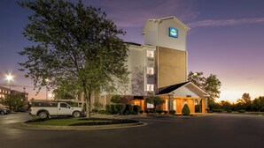 A hotel with a prominent tower, a parking lot, and a well-lit entrance.