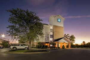 A hotel with a prominent tower, a parking lot, and a well-lit entrance.