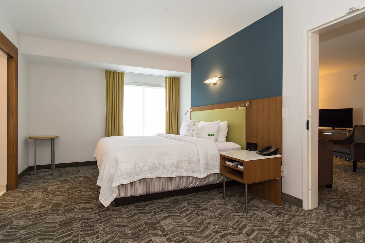 A hotel room with a bed, bedside table, and a desk with a chair.