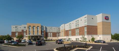 A multi-story hotel with a parking lot in front.