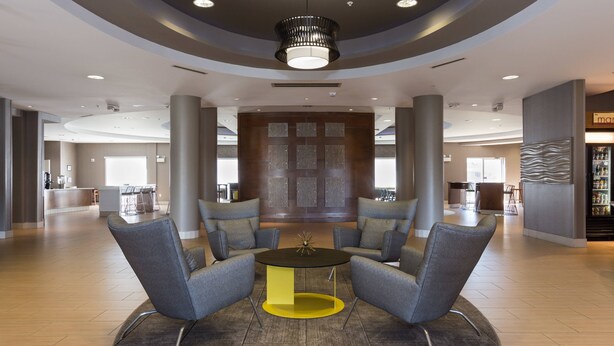 A spacious lobby with a central seating area, a reception desk, and a modern light fixture.