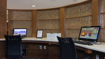 Un centro de negocios con dos estaciones de trabajo de computadora, una impresora y un cartel que indica su ubicación.