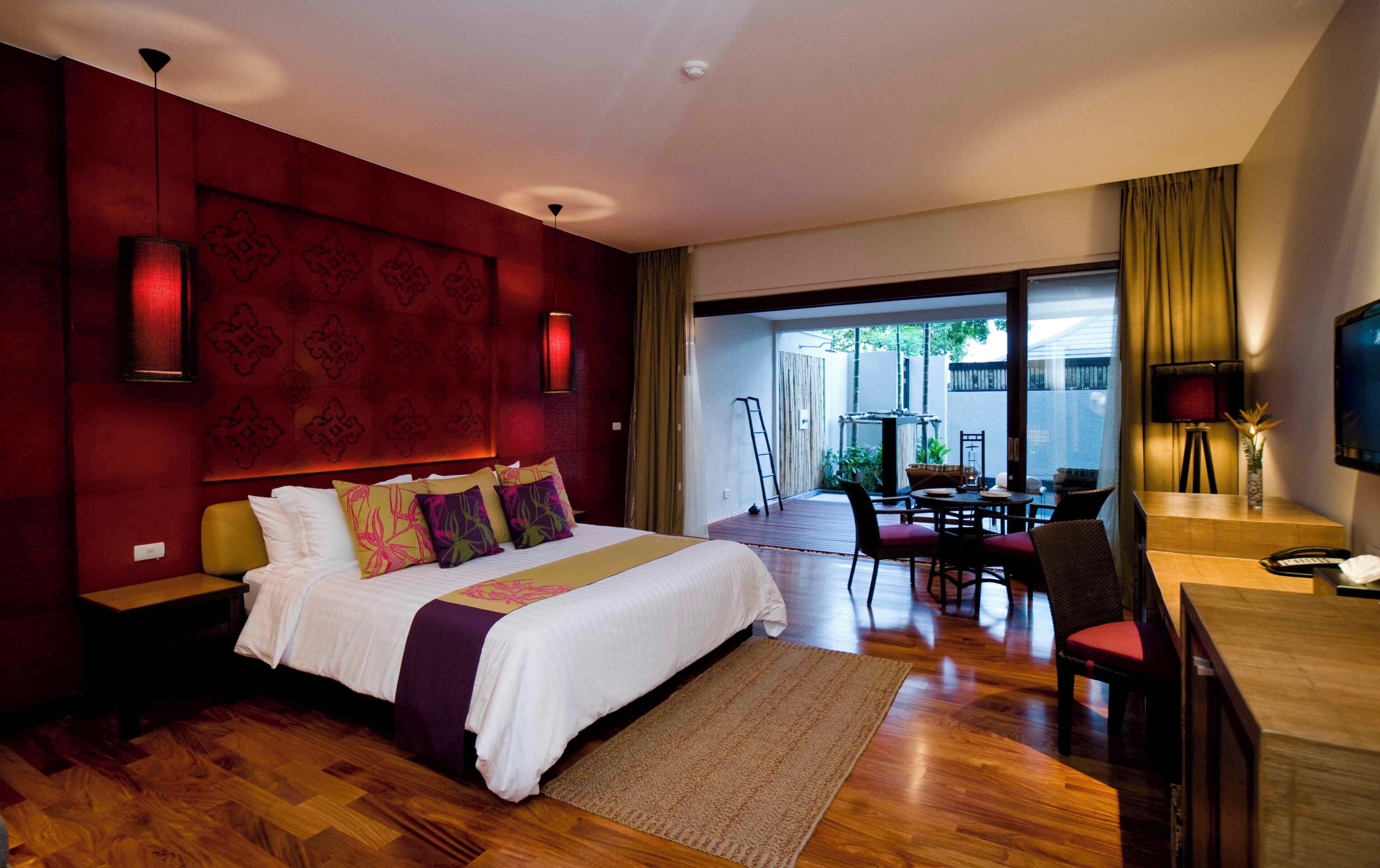 A hotel room with a large bed, a dining area, and a view of the outdoors.