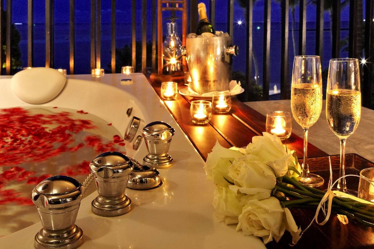 A romantic dinner setup with a table, candles, champagne, and flowers.