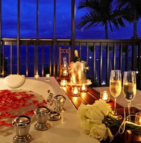 Una cena romántica con una mesa, velas, champán y flores.