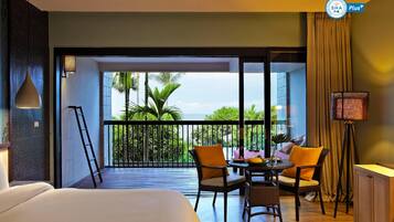 Une chambre d’hôtel avec un balcon, un lit, une table avec des chaises et une vue sur la mer.