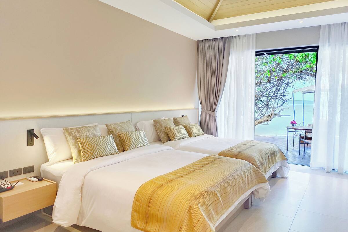 A modern hotel room with a large bed, bedside tables, and a view of the outdoors.