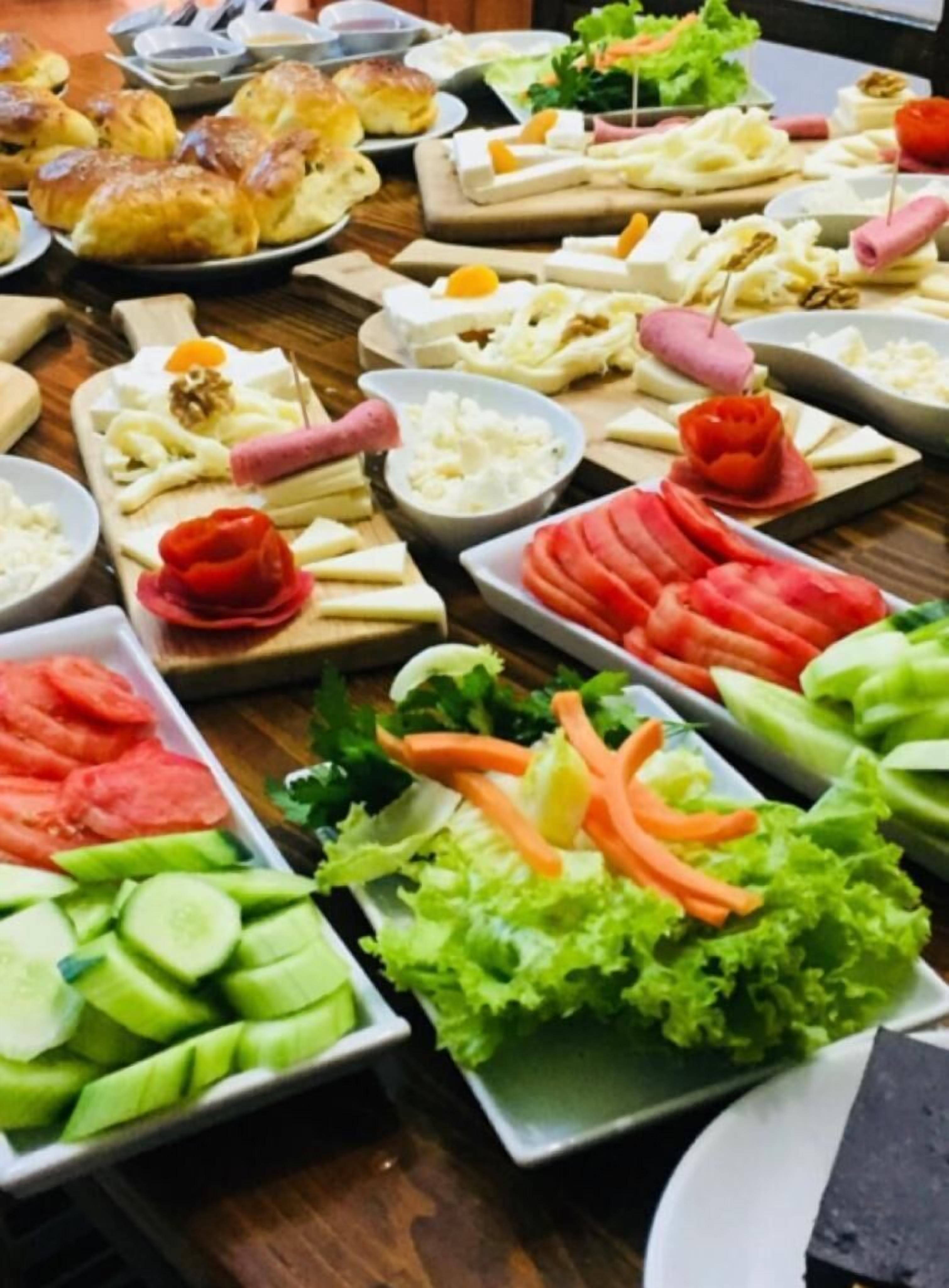 A buffet with various food items including bread, cheese, vegetables, and meats.