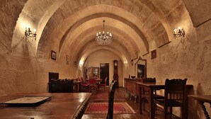 A dimly lit room with arched ceilings, a chandelier, wooden furniture, and a red carpet. - Elif Stone House (Ürgüp)
