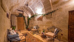 A cozy room with a stone ceiling, a wooden door, and a patterned rug. - Elif Stone House (Ürgüp)