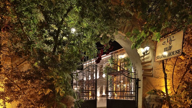 A stone house with a sign reading "elf HOUSE" surrounded by lush greenery and a well-lit entrance. - Elif Stone House (Ürgüp)