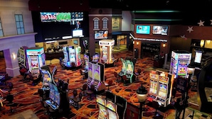 Een speelruimte van een casino met meerdere gokkasten en enkele blackjack tafels.