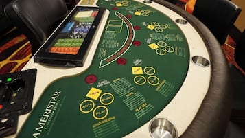 A blackjack table with a green felt surface, a digital card reader, and a cash box.