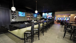 Een bar met een toog, meerdere televisies en een zithoek met stoelen en tafels.