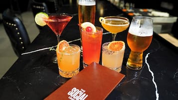 A bar setting with various drinks, a menu, and bar chairs.