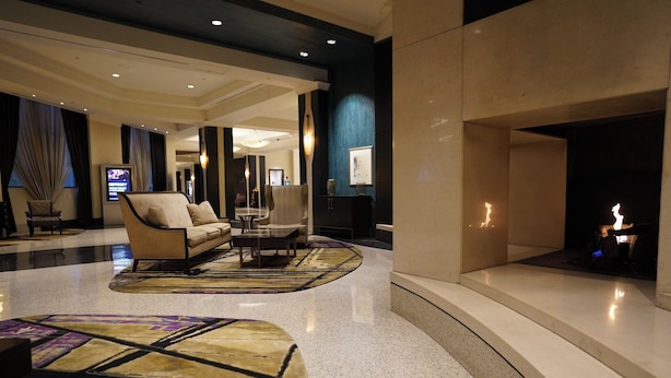 Een moderne lobby met een bank, salontafel en een open haard.