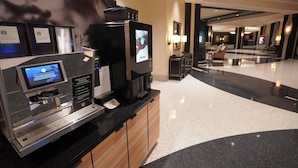 Een moderne hotel lobby met een koffiehoek, zithoek en een receptiebalie.