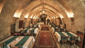 A long dining hall with tables and chairs, a central chandelier, and a patterned carpet. - Cappadocia Palace Hotel (Ürgüp)