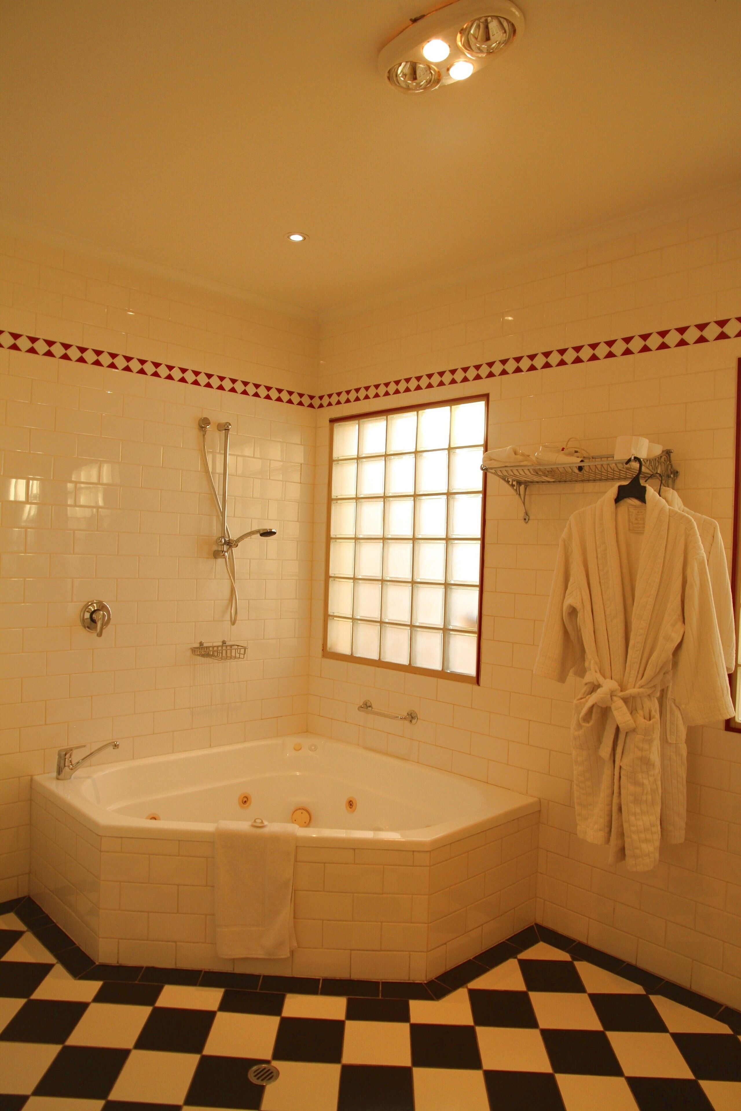 Une salle de bain avec une grande baignoire, une fenêtre et un porte-serviettes avec un peignoir.