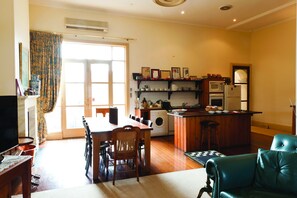 A compact living space with a dining area, kitchen, and a green armchair. - Fire Station Inn (North Adelaide)