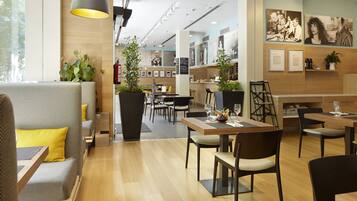 A modern hotel lobby with seating areas, a bar, and artwork on the walls.
