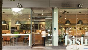 A cafe with a glass storefront, outdoor seating, and a visible menu board. - Zinema7 (San Sebastián)