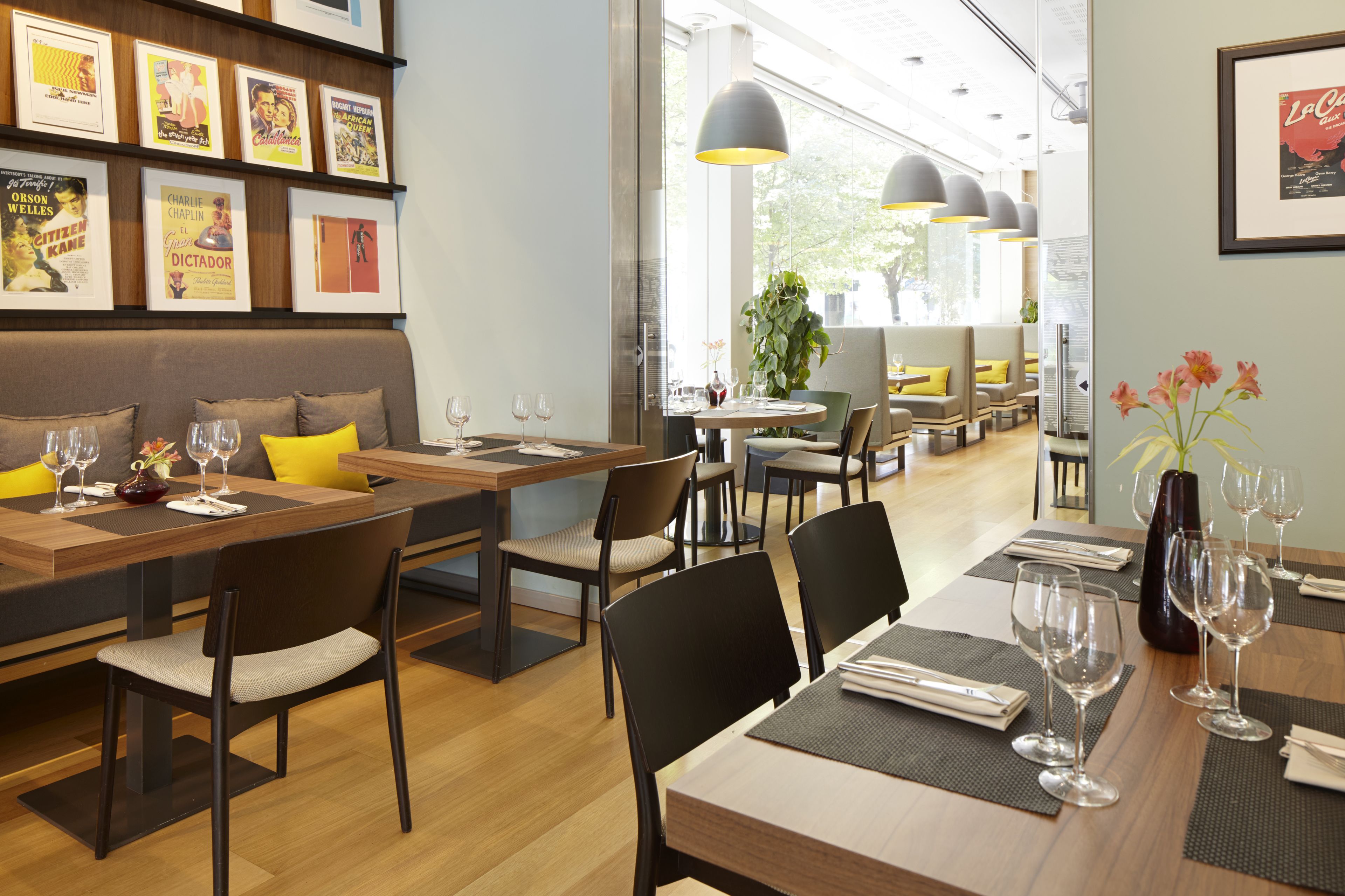 Un ristorante con diversi tavoli, sedie e una parete decorata con quadri.