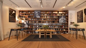 A library with wooden bookshelves, a central table with chairs, and framed pictures on the walls. - Zinema7 (San Sebastián)