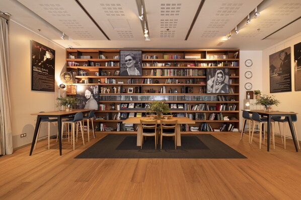 A library with wooden bookshelves, a central table with chairs, and framed pictures on the walls. - Zinema7 (San Sebastián)
