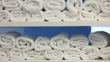 Two shelves stacked with neatly rolled white towels.