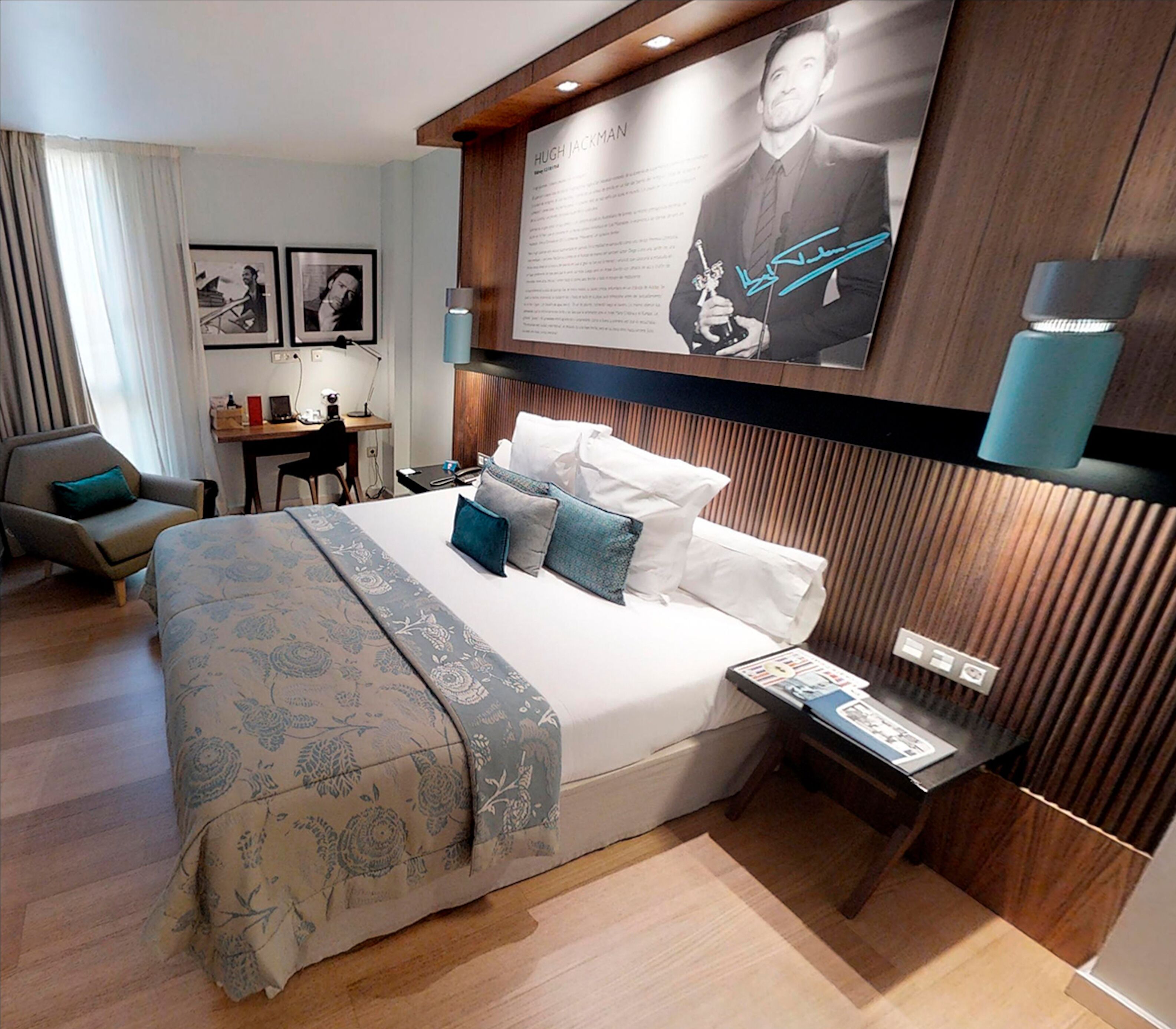 Una habitación de hotel moderna con una cama grande, un escritorio, una silla y un televisor de pared que muestra un cartel con firma.