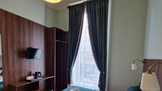 Une chambre d’hôtel avec un lit, une télévision, un bureau et une fenêtre avec des rideaux.