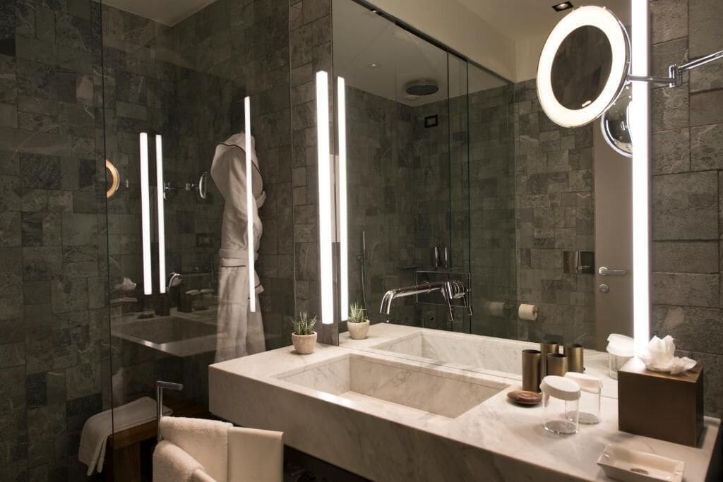 A modern bathroom with a large mirror, a dual sink vanity, and a glass-enclosed shower area.