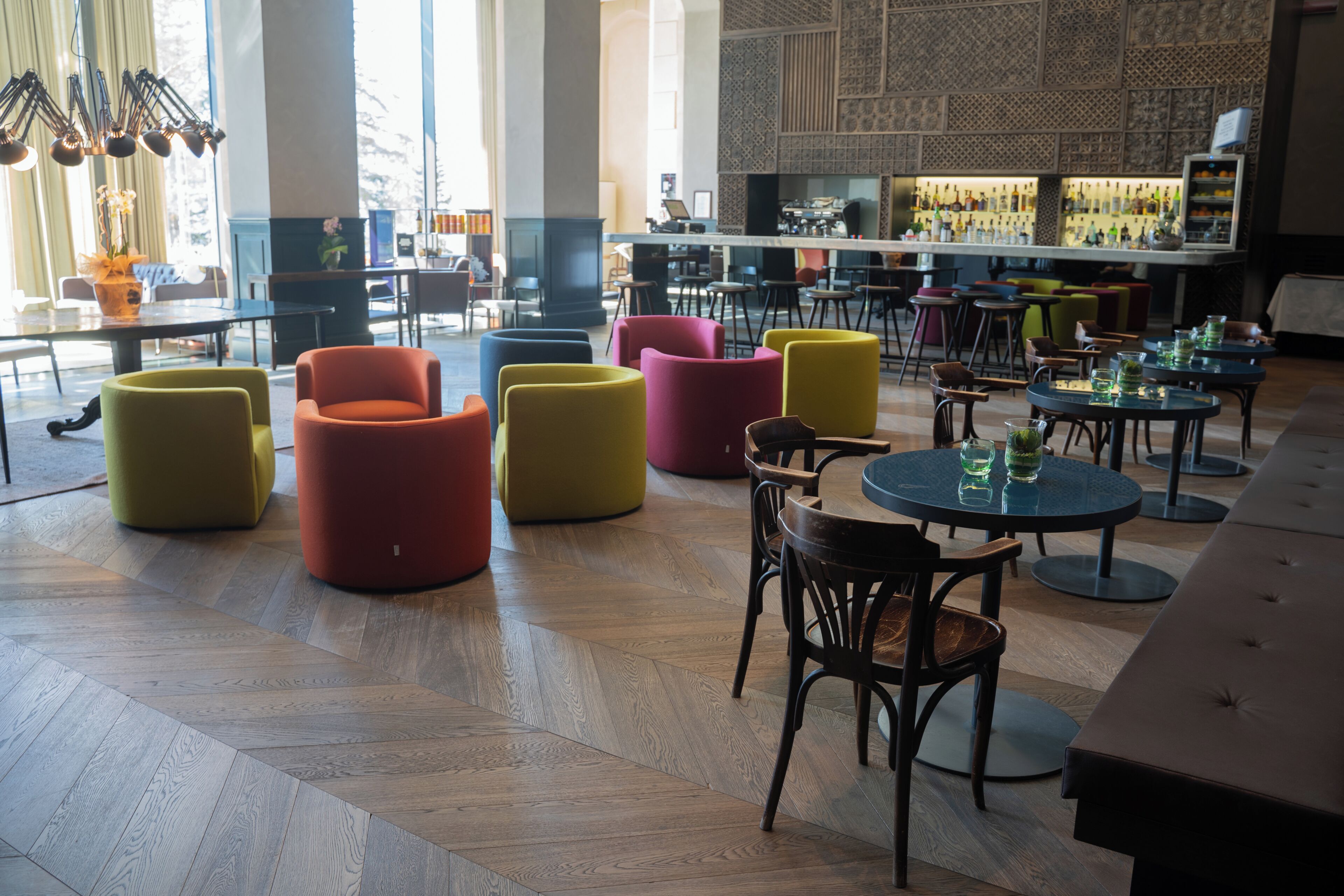 A modern interior with a bar area, seating arrangements, and a patterned wall.