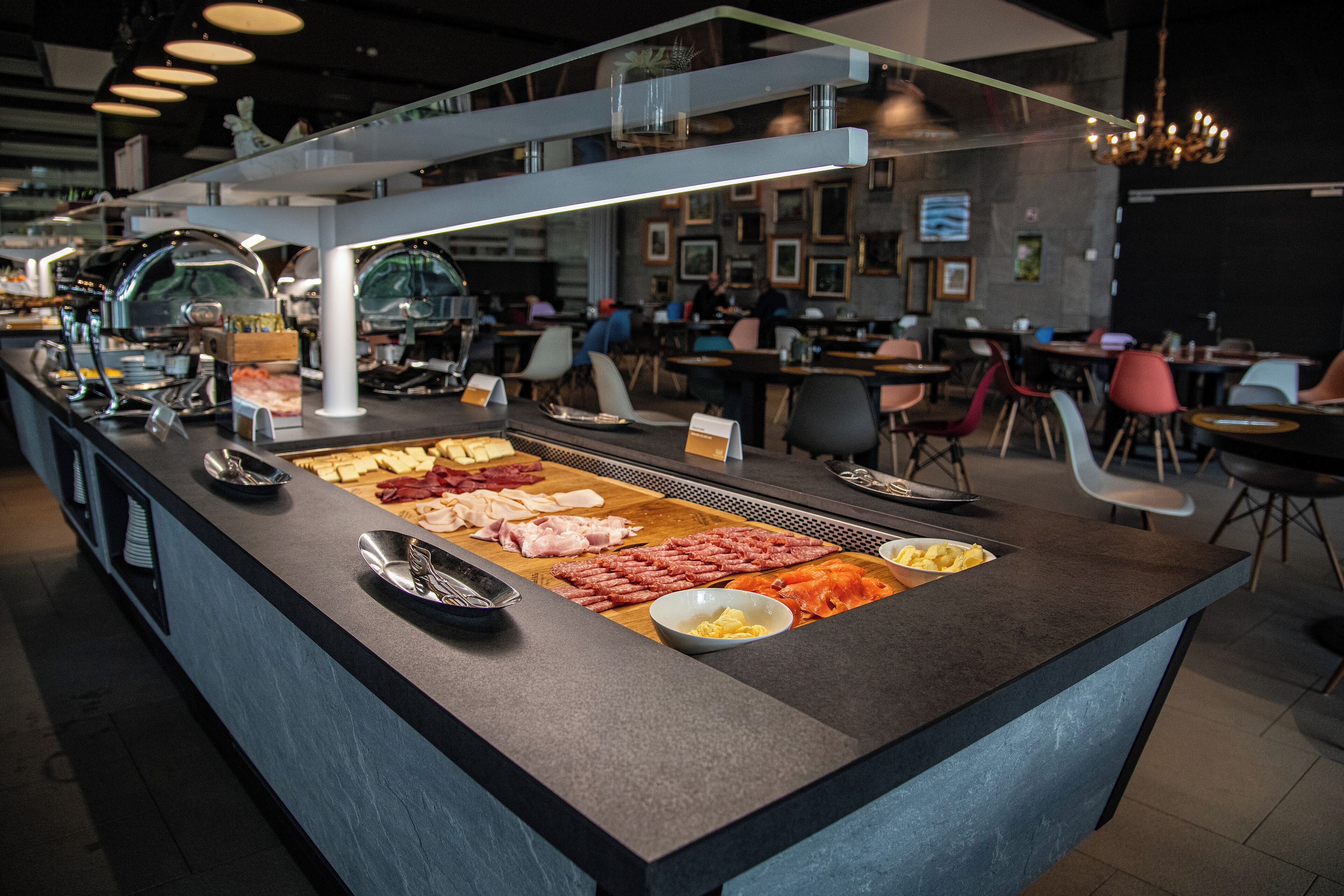 A buffet counter with various meats and cheeses.