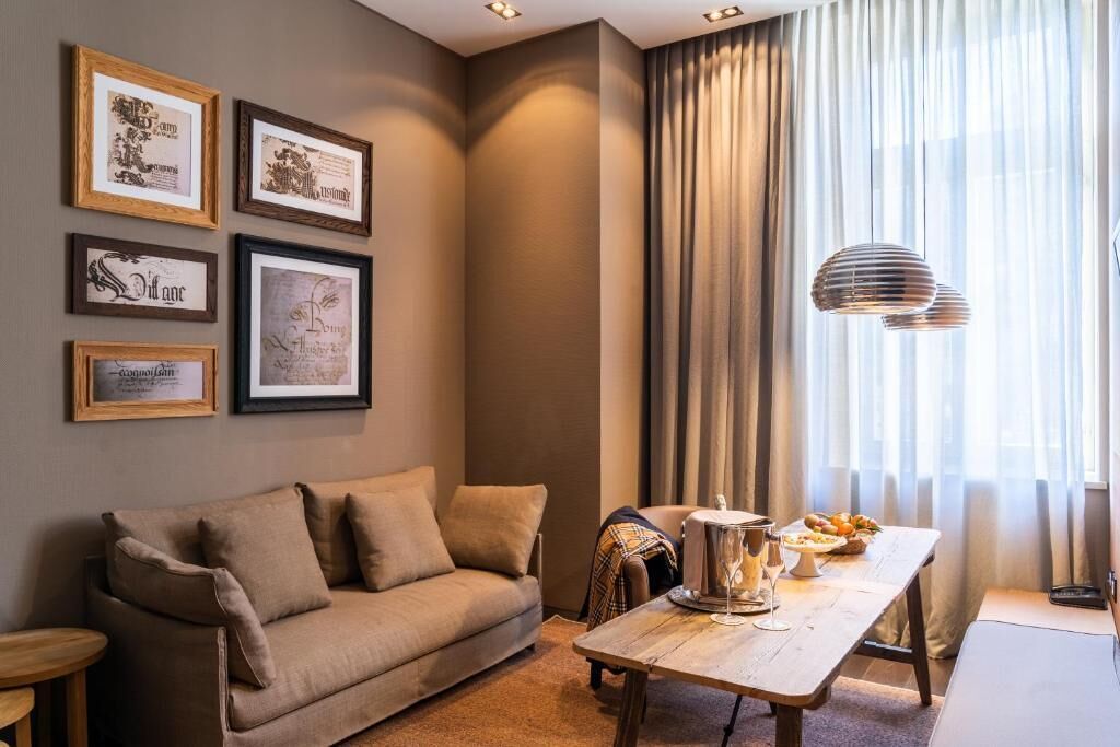 A cozy living room with a sofa, a dining table with a lamp, and framed certificates on the wall.