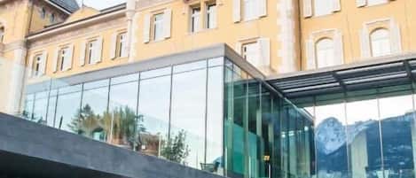 A modern building with a glass facade and a pool area with steam rising from the water.