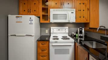 Una cocina con armarios de madera, un refrigerador blanco, un microondas, una estufa y un lavaplatos.