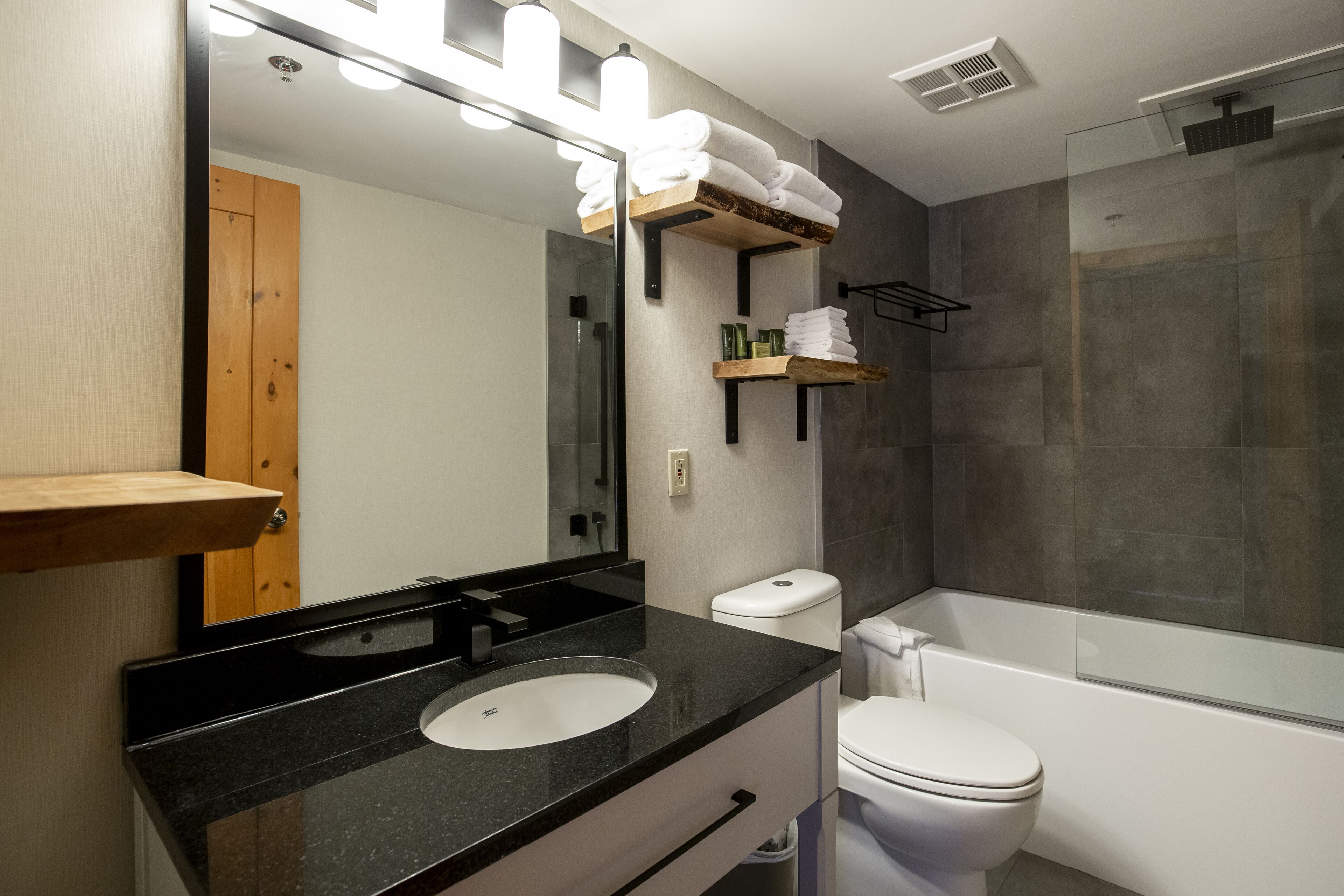 Un bagno moderno con lavabo su piano nero, water bianco e cabina doccia in vetro.