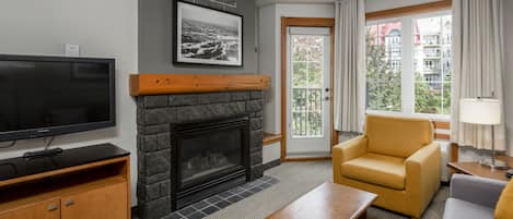 Una sala de estar moderna con chimenea, televisor, sofá y sillón.